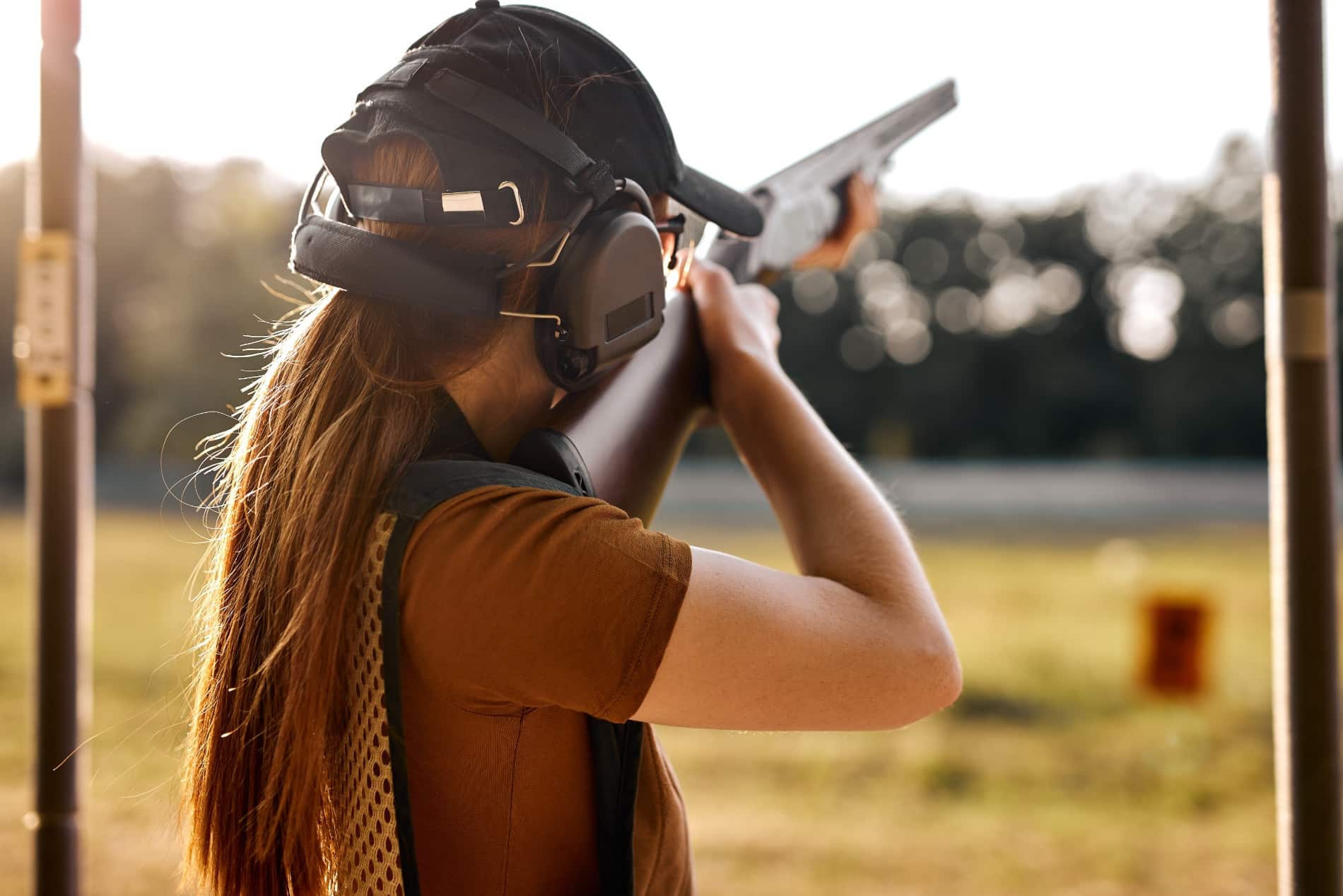 woman shooting shotgun down range outdoors